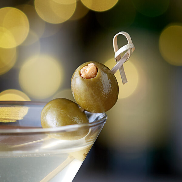 A martini with Belosa Cheddar Cheese Stuffed Queen Olives on a bamboo pick.