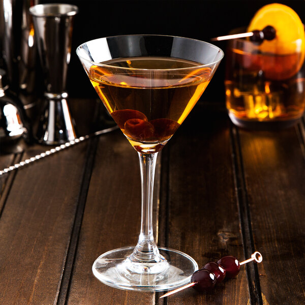 A martini glass with a Fabbri Amarena cherry on a stick sitting on a table.