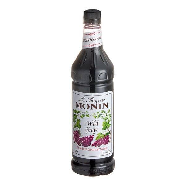 A close up of a Monin Wild Grape Syrup bottle with a label.