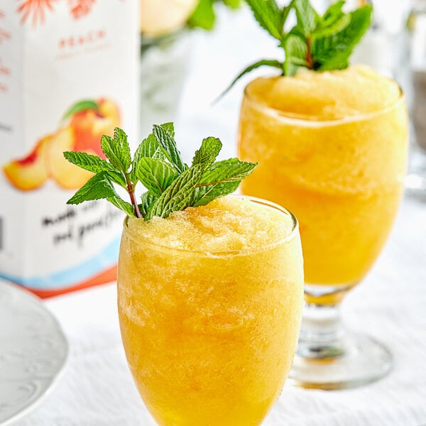 Two glasses of Island Oasis peach smoothie with mint leaves.