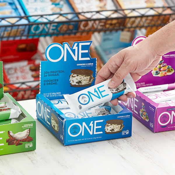 A hand holding a package of ONE Cookies and Creme Protein Bars.