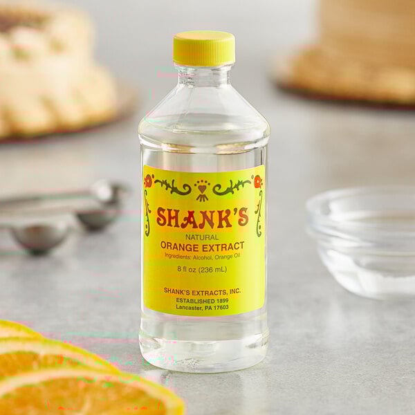 A bottle of Shank's orange extract on a counter next to a cake.