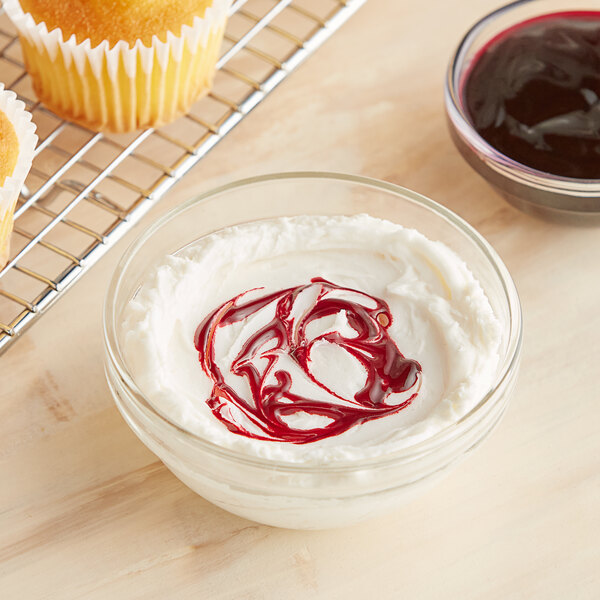 A bowl of cream with red food coloring on top of a cupcake.
