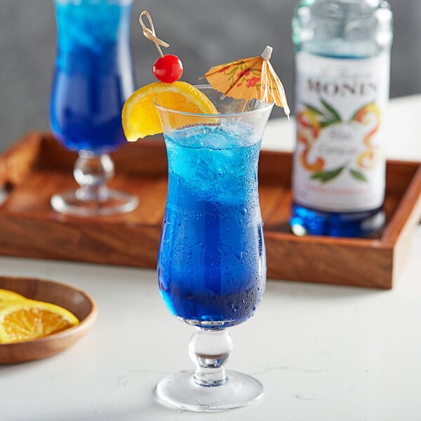 A blue drink in a blue glass with a slice of orange on top.