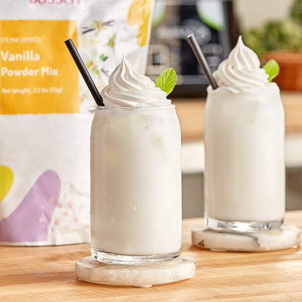 Two glasses of vanilla milk with straws next to a bag of Bossen vanilla powder.