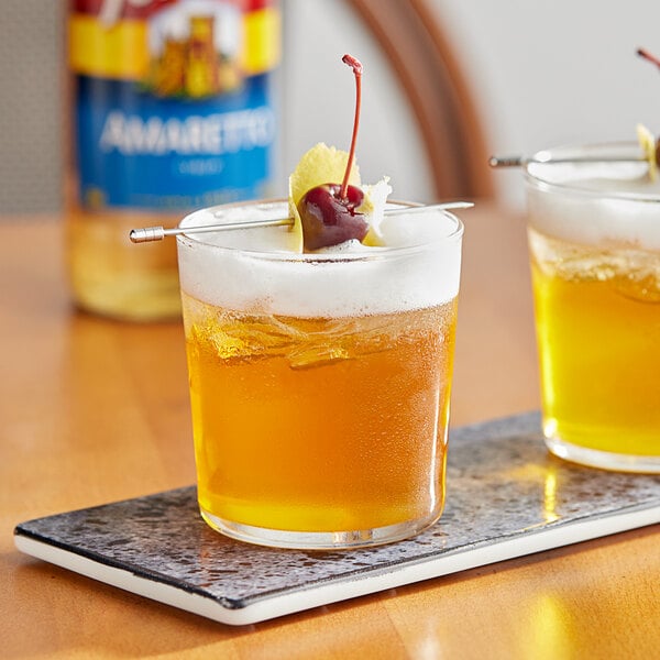 Two glasses of Torani Amaretto flavoring syrup with cherries on a tray.