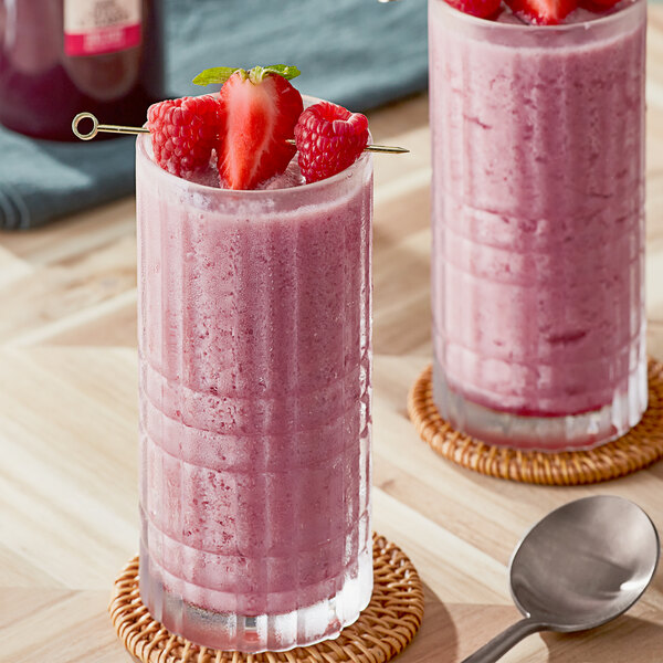 Two glasses of pink smoothie made with SHOTT Three Berry syrup with strawberries and raspberries.