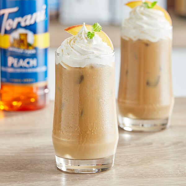 Two glasses of iced coffee with Torani Sugar-Free Peach Syrup and whipped cream and orange slices on top.