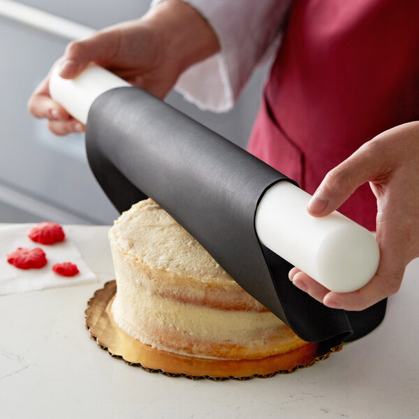 A person using Satin Ice ChocoPan black covering chocolate to cover a cake.