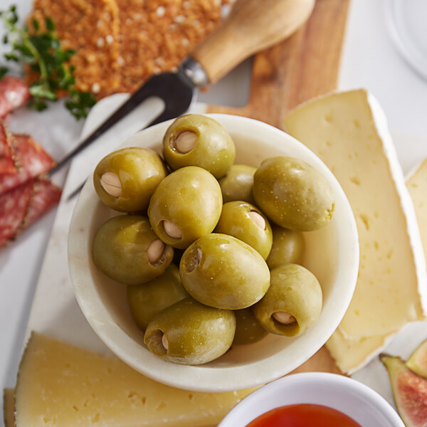 A bowl of Belosa almond stuffed green olives on a table with cheese.