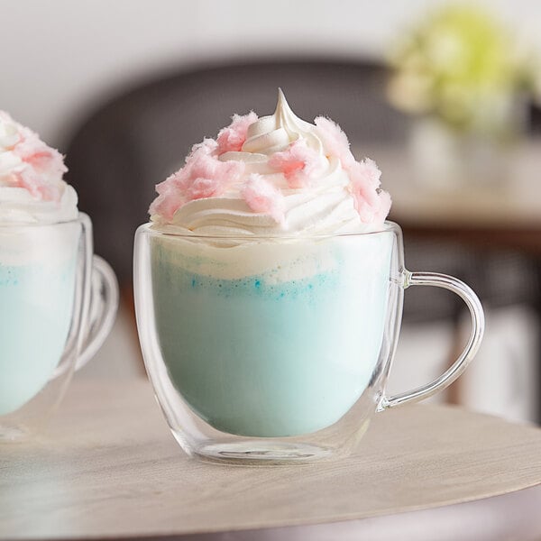 Two clear mugs with blue liquid and pink cotton candy on top.