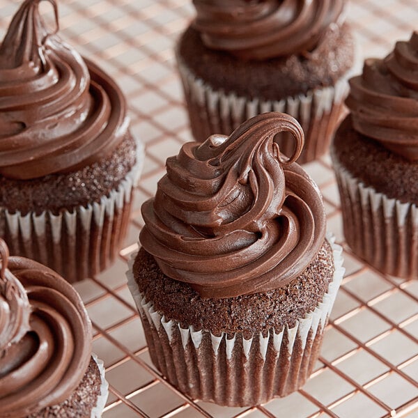 A chocolate cupcake with chocolate frosting on a cooling rack.