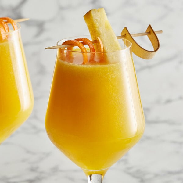 A glass of yellow liquid with a straw and an orange slice on the rim.