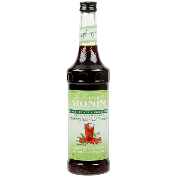 A close up of a Monin Raspberry Tea Concentrate bottle with a label.