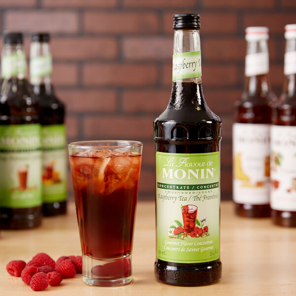 A Monin bottle of raspberry tea concentrate with a green label.