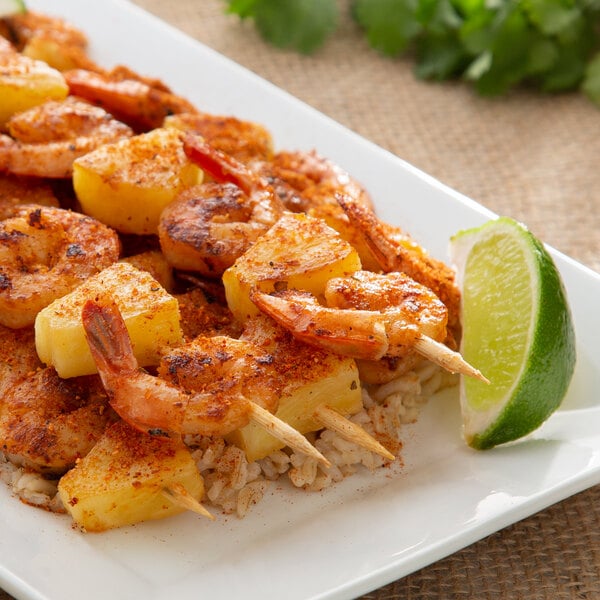 A plate of food with shrimp, rice, and a lime wedge seasoned with Regal Caribbean Sunrise Jerk Seasoning.