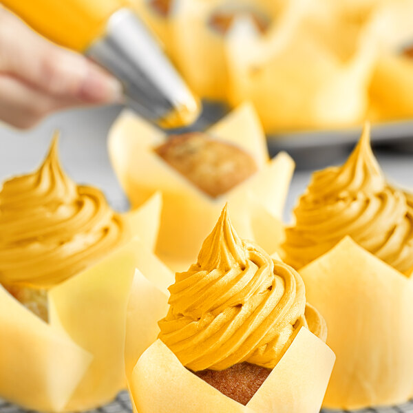 A close-up of a cupcake with yellow swirled frosting.