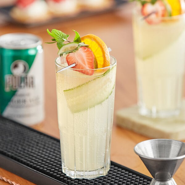 A glass of liquid with fruit slices and a can of Polar ginger ale.