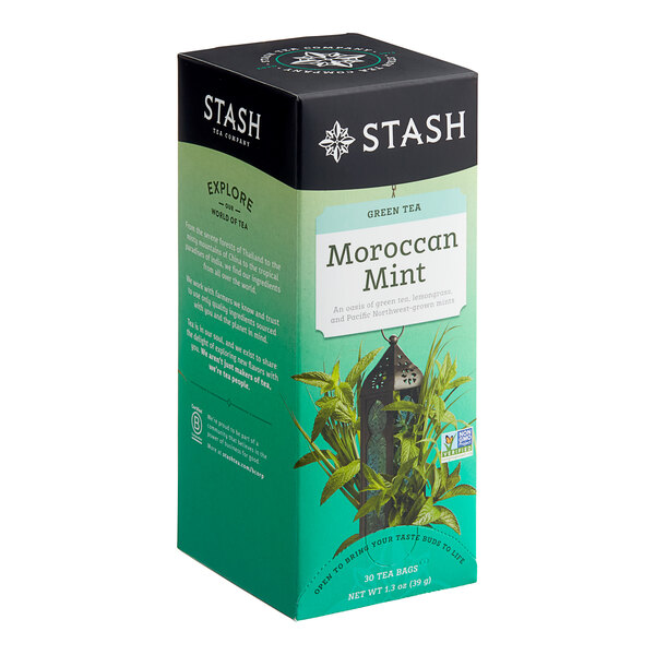 A box of Stash Moroccan Mint Green Tea Bags on a table in an organic food store with a picture of a plant.