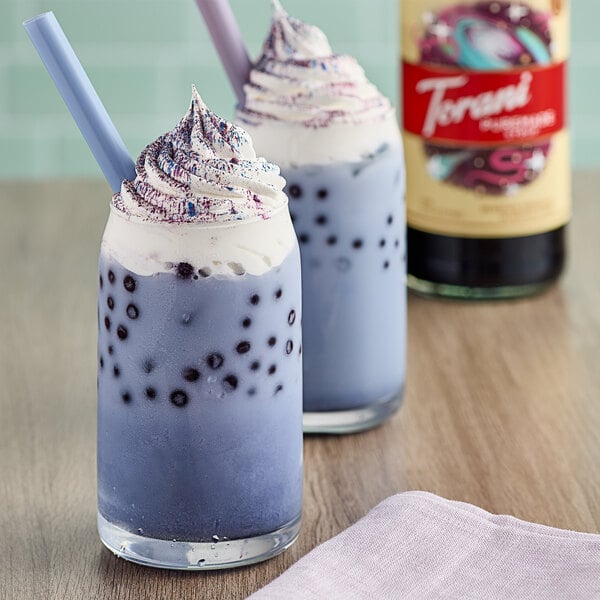 Two glasses of purple Galaxy Bubble Tea with whipped cream and sprinkles.