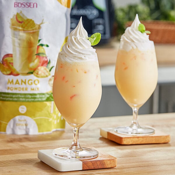 Two glasses of mango juice made with Bossen Mango Powder on a table in a smoothie shop.