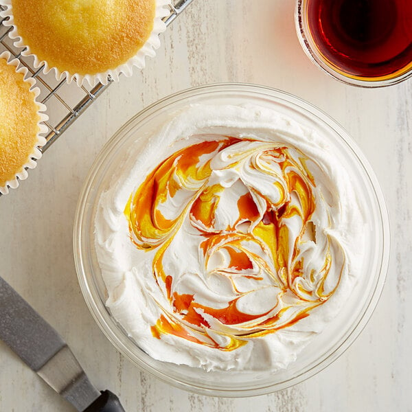 Whipped cream with yellow and orange swirls on a cupcake.