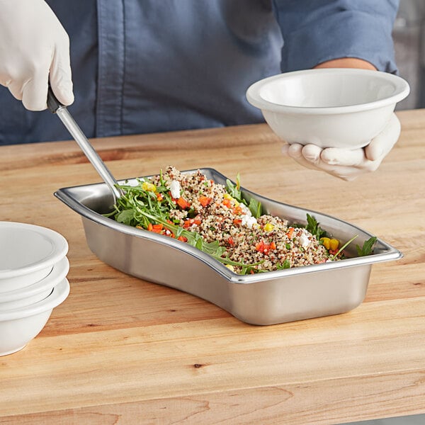A person using a Vollrath stainless steel bowl to prepare food at a salad bar.