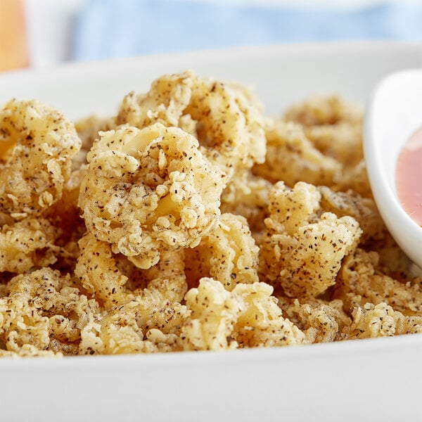 A plate of fried shrimp with a white bowl of Regal Salt and Pepper Seasoning Blend.