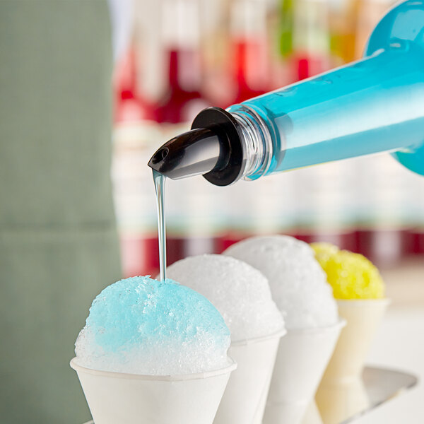 A person pouring blue Hawaiian Shaved Ice syrup onto a bowl of white and blue shaved ice.