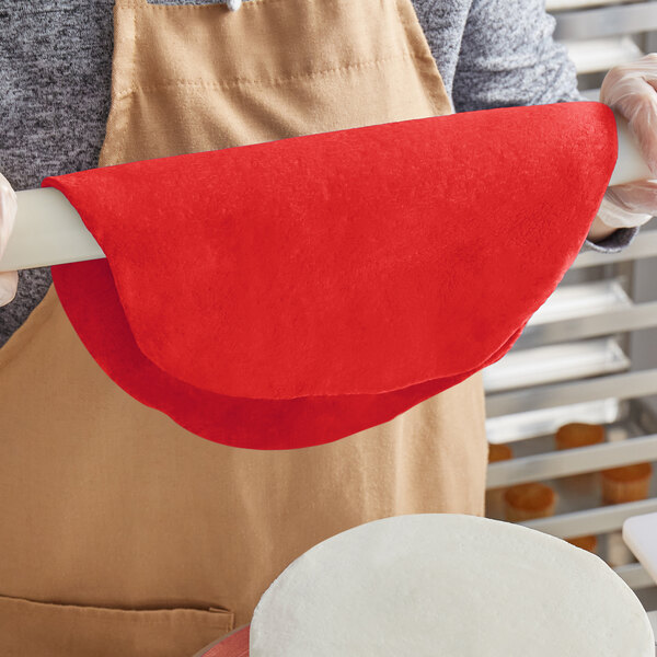 A person rolling red Satin Ice Dream chocolate-flavored fondant with a red cloth-covered rolling pin.