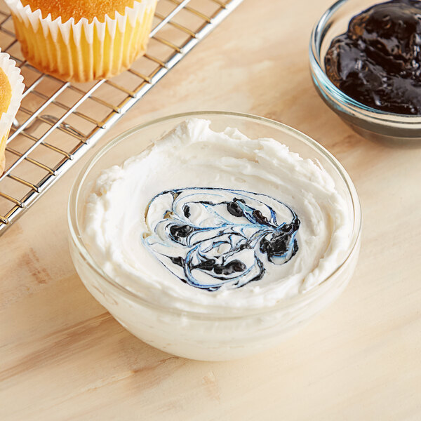 A bowl of blue and white swirled frosting with a cupcake.