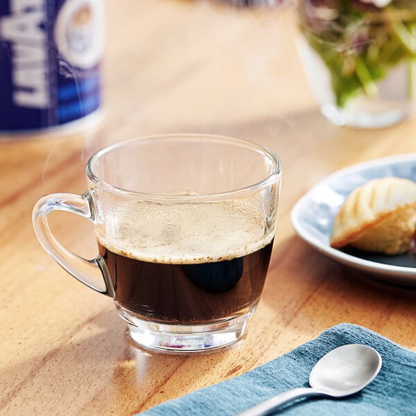 A glass of Lavazza In Blu ground espresso on a table with a spoon.