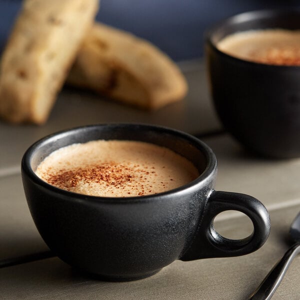 A close-up of a cup of chai tea with a spoon and a cookie.