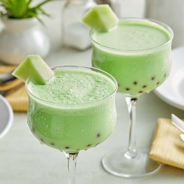 Two glasses of Fanale Honeydew powder mixed green bubble tea with green straws.