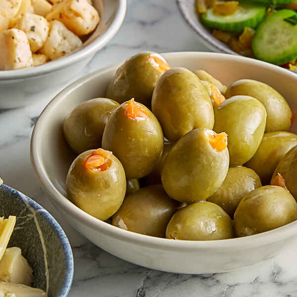 A bowl of Belosa Cream Cheese & Habanero Stuffed green olives on a table with other food.