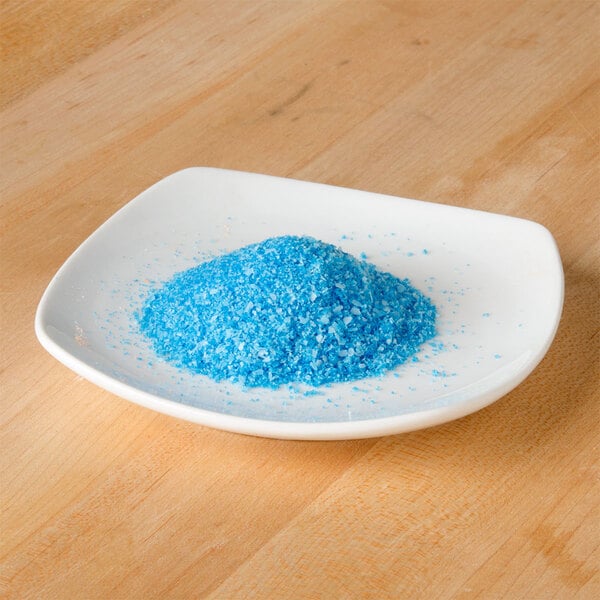 A small white plate with blue crystals on it.