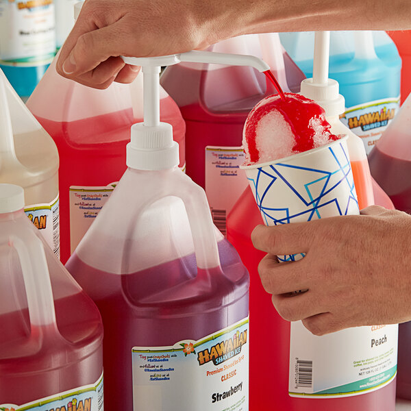 A close-up of a jug of red liquid with a white label that reads "Hawaiian Shaved Ice Strawberry Snow Cone Syrup" being poured into a drink.