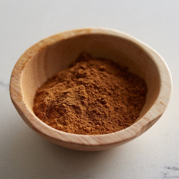 A bowl of Regal Ground Cinnamon powder on a table.