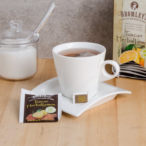 A cup of Bromley Tuscan Lemon herbal tea on a table with a packet of tea.