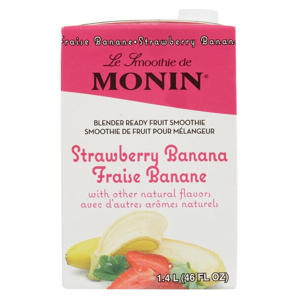 A carton of Monin strawberry banana fruit smoothie mix with a banana and strawberries on a plate.