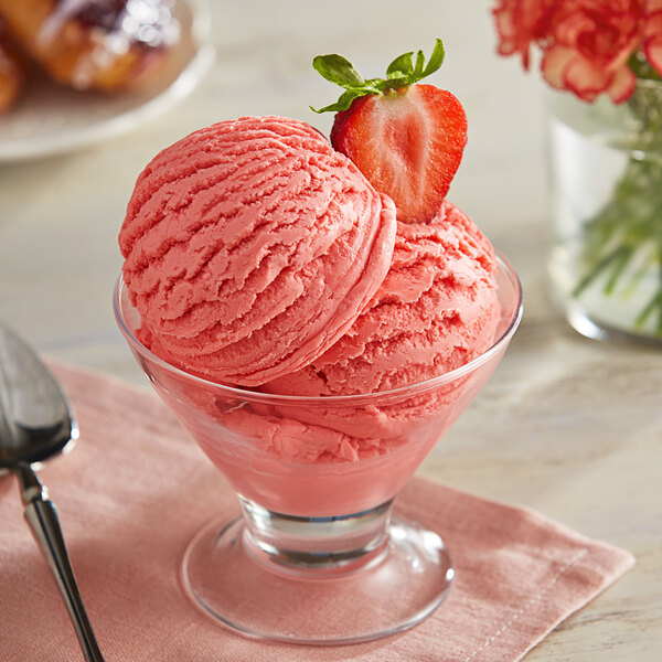A bowl of strawberry ice cream with a strawberry on top.