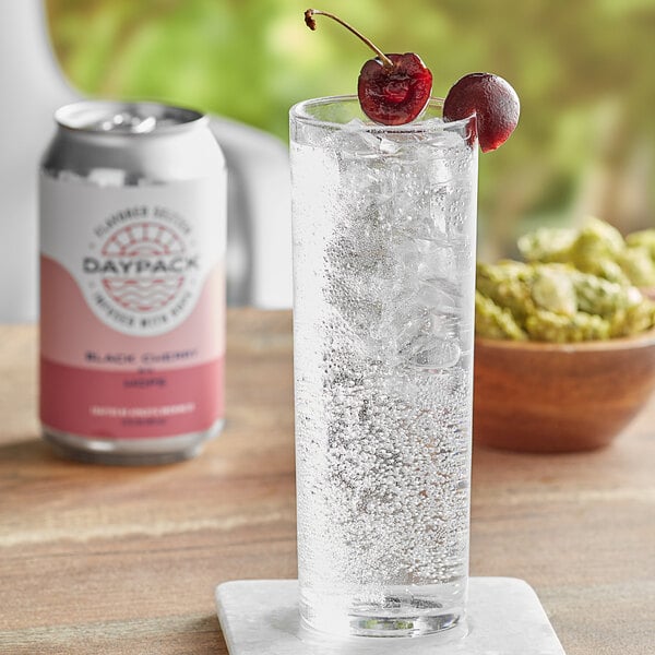 A glass of black cherry DayPack sparkling water with bubbles and cherries.