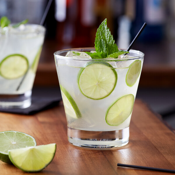 A glass of Monin key lime liquid with ice and lime slices.