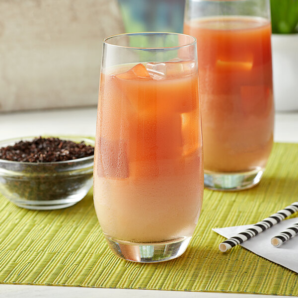 A glass of iced coffee black tea with a bowl of loose leaf tea in the background.