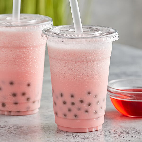 A pink bubble tea in a plastic cup with a straw and black balls.