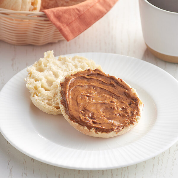 A white plate with a biscuit spread with American Almond roasted almond butter.