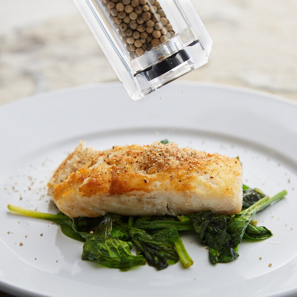 A plate of food with a pepper mill on the table.