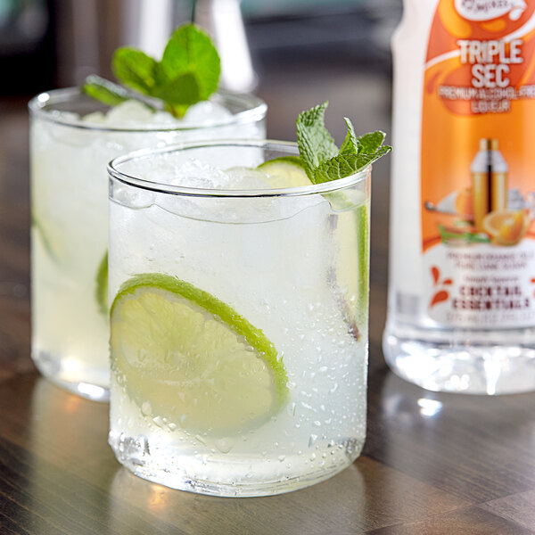 Two glasses of Master of Mixes Triple Sec with lime slices and mint leaves on a white background.