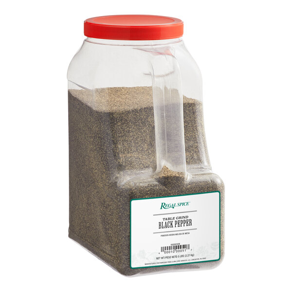 A plastic container of Regal Table Grind Ground Black Pepper with a red lid and black pepper inside.