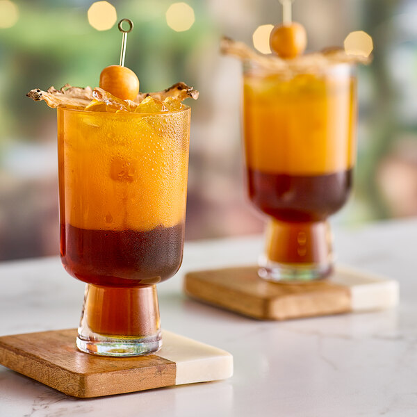 Two glasses of Tiki Breeze Hibiscus Gold Tiki Energy drink on a table.